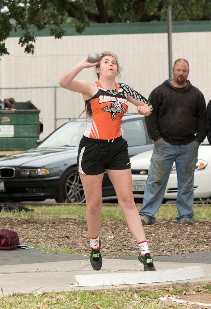 Athlete prepares for pole vault on a track with others watching.