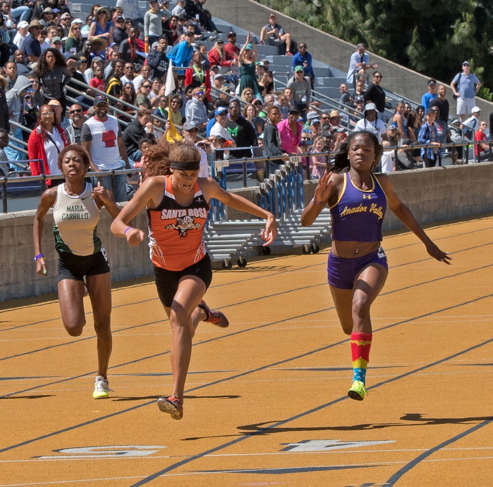 Athlete prepares for pole vault on a track with others watching.