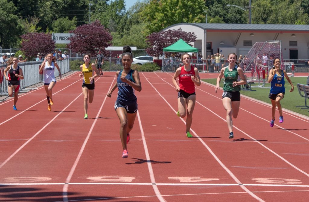 Athlete prepares for pole vault on a track with others watching.