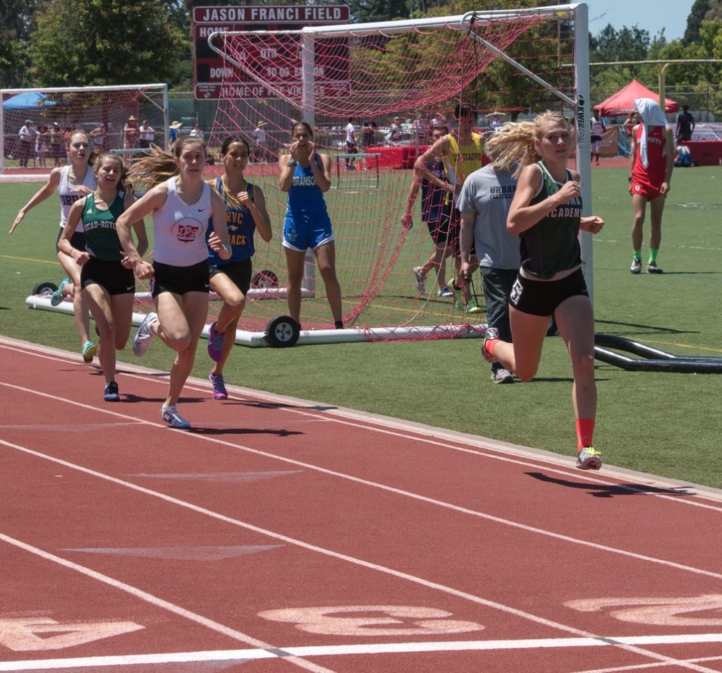 Athlete prepares for pole vault on a track with others watching.