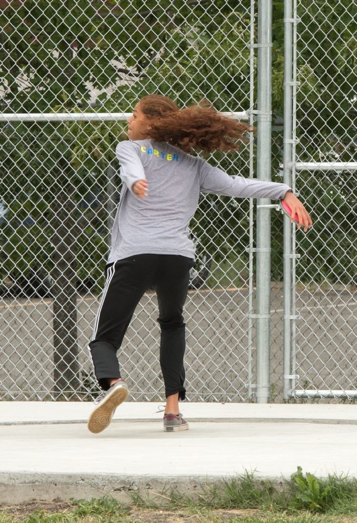 Athlete prepares for pole vault on a track with others watching.