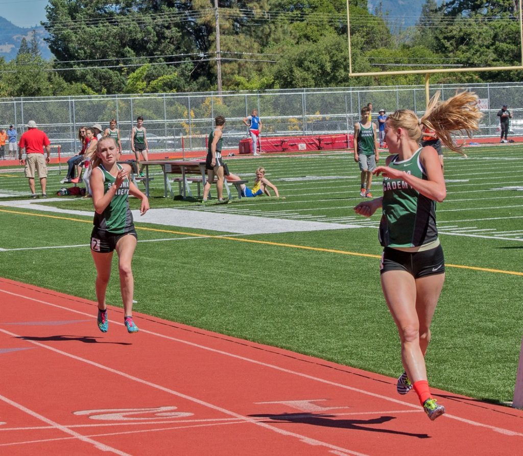 Athlete prepares for pole vault on a track with others watching.