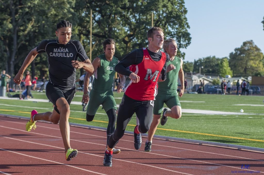 Athlete prepares for pole vault on a track with others watching.