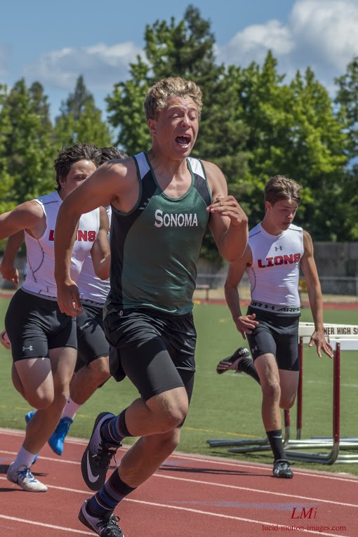 Athlete prepares for pole vault on a track with others watching.