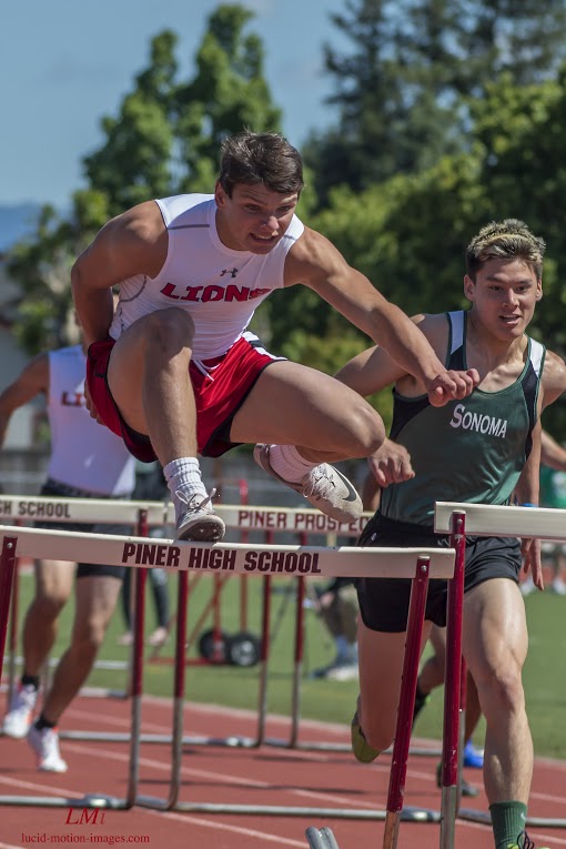 Athlete prepares for pole vault on a track with others watching.