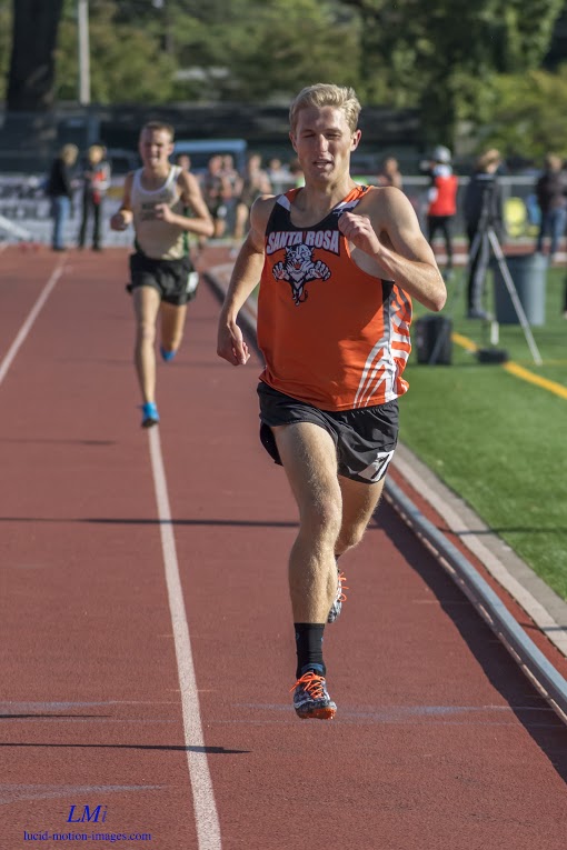 Athlete prepares for pole vault on a track with others watching.