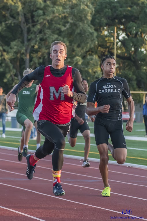 Athlete prepares for pole vault on a track with others watching.