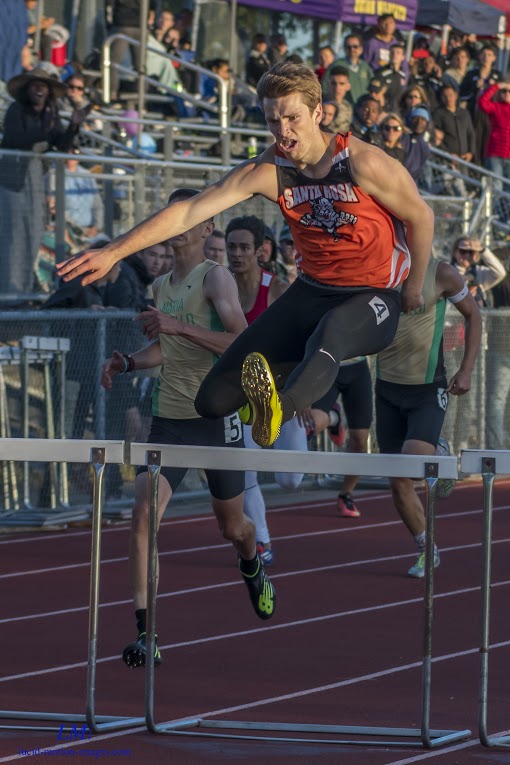 Athlete prepares for pole vault on a track with others watching.