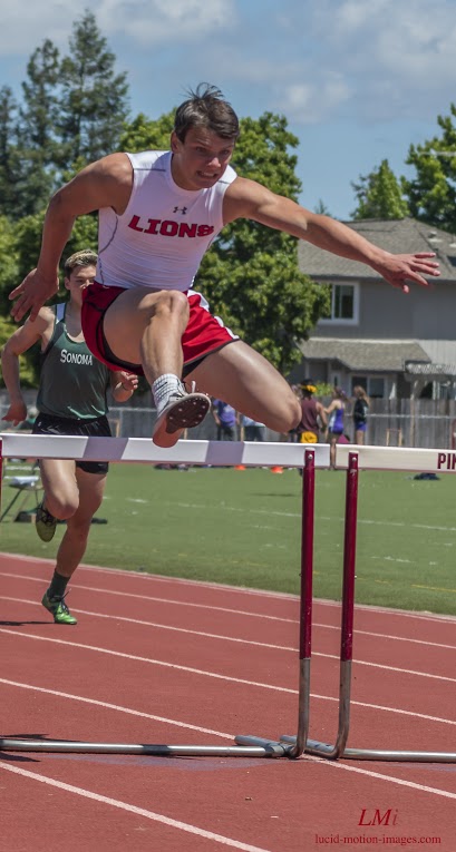 Athlete prepares for pole vault on a track with others watching.