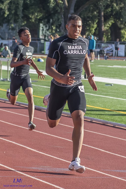 Athlete prepares for pole vault on a track with others watching.