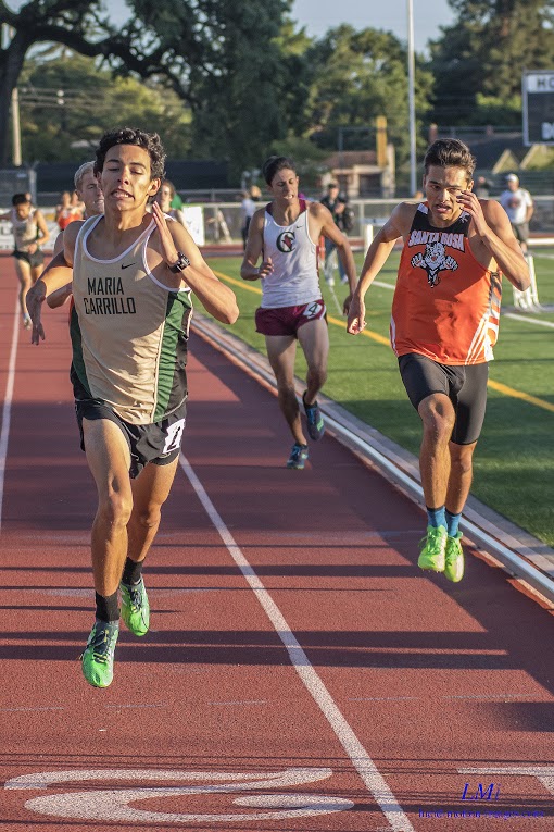 Athlete prepares for pole vault on a track with others watching.