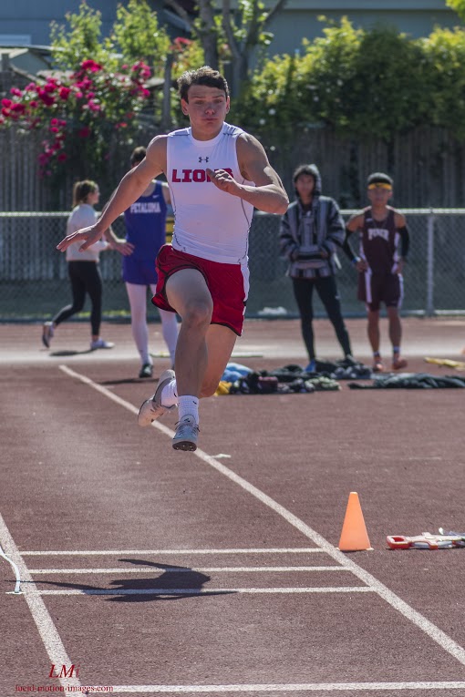 Athlete prepares for pole vault on a track with others watching.
