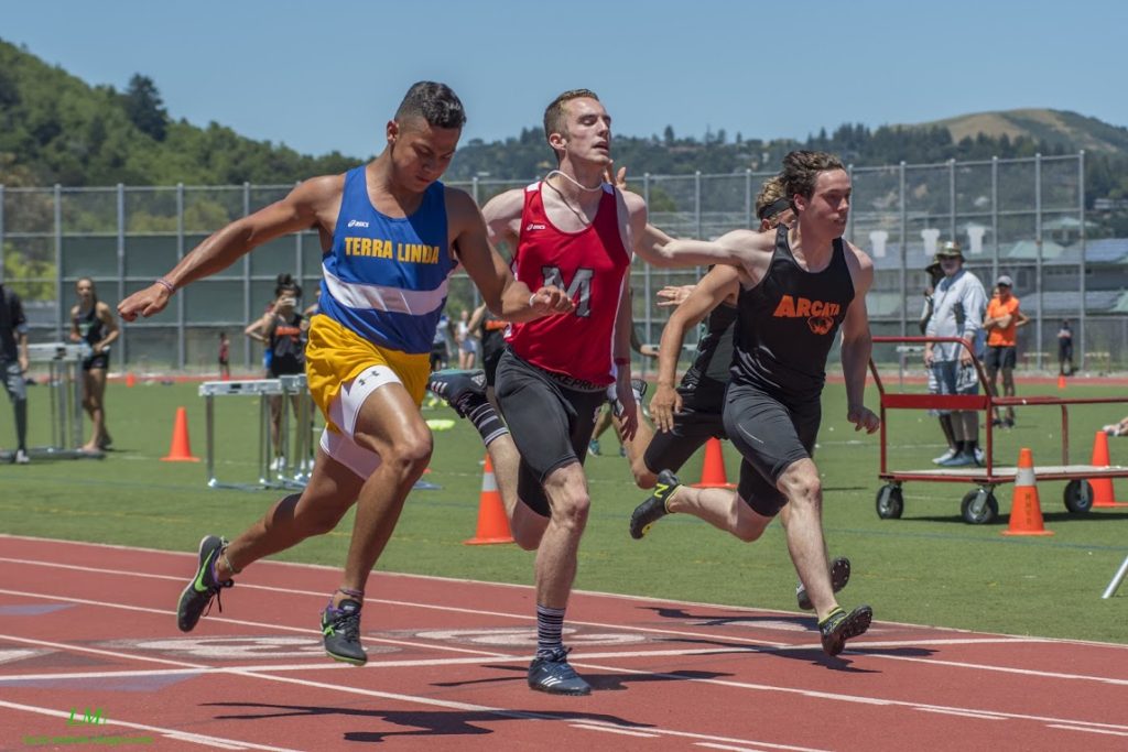 Athlete prepares for pole vault on a track with others watching.