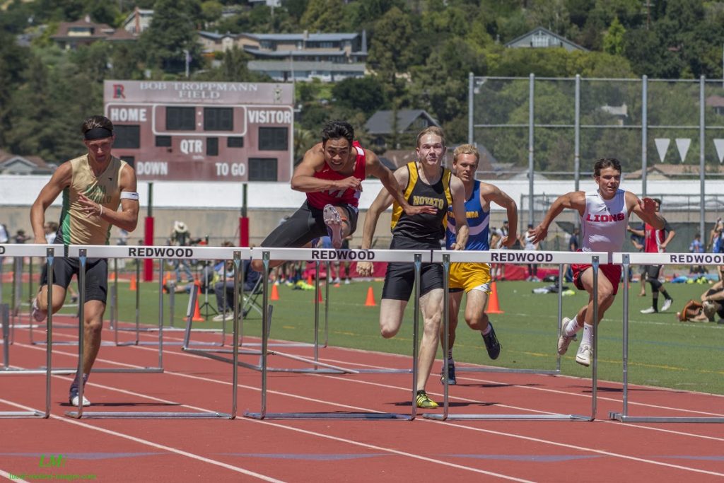 Athlete prepares for pole vault on a track with others watching.