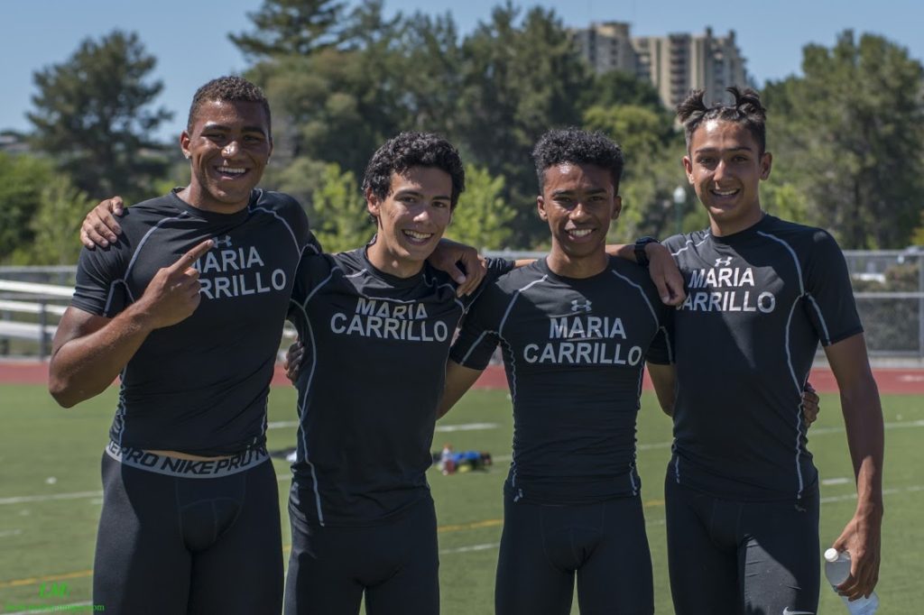 Athlete prepares for pole vault on a track with others watching.