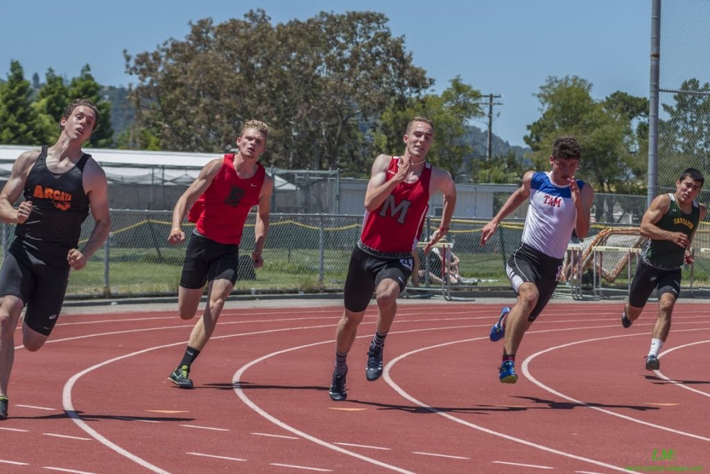 Athlete prepares for pole vault on a track with others watching.