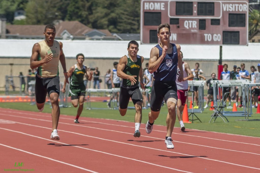 Athlete prepares for pole vault on a track with others watching.