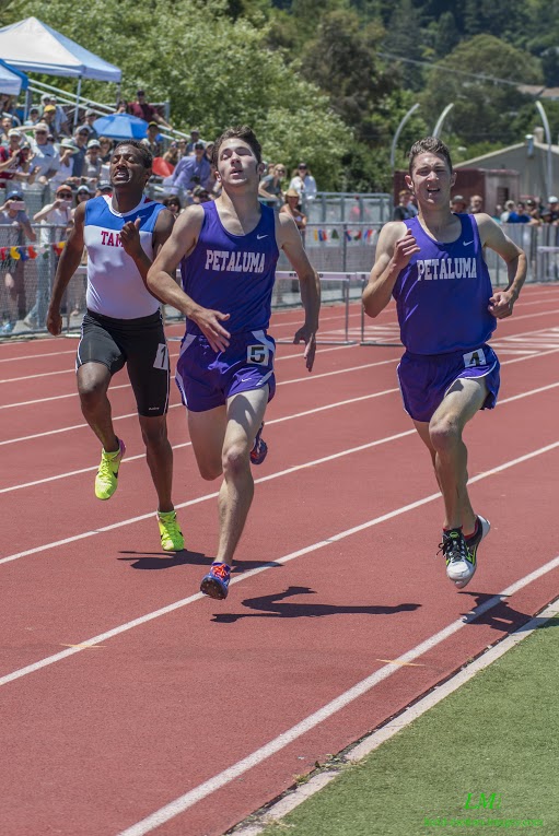 Athlete prepares for pole vault on a track with others watching.