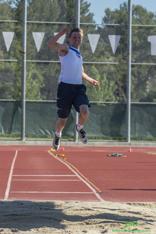 Athlete prepares for pole vault on a track with others watching.