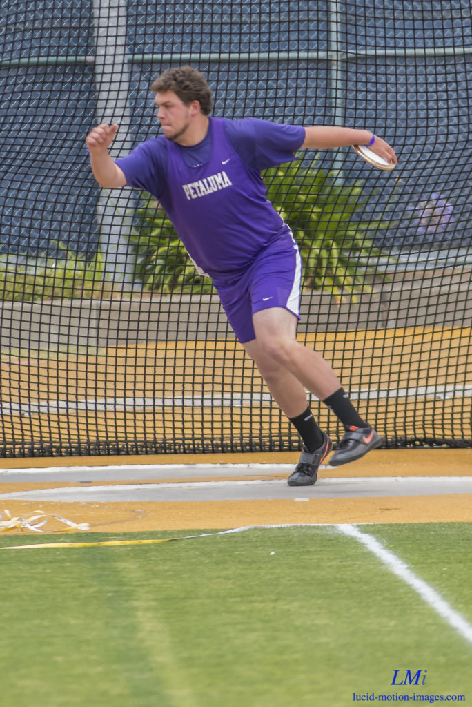 Athlete prepares for pole vault on a track with others watching.