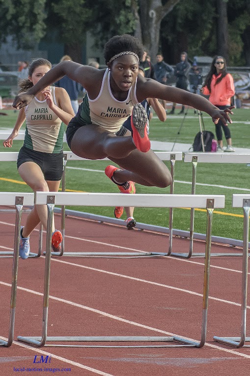 Athlete prepares for pole vault on a track with others watching.