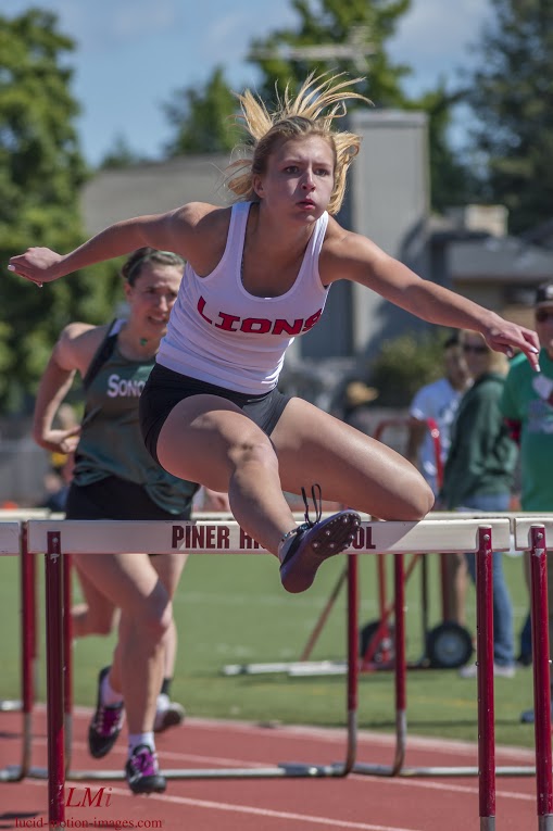 Athlete prepares for pole vault on a track with others watching.