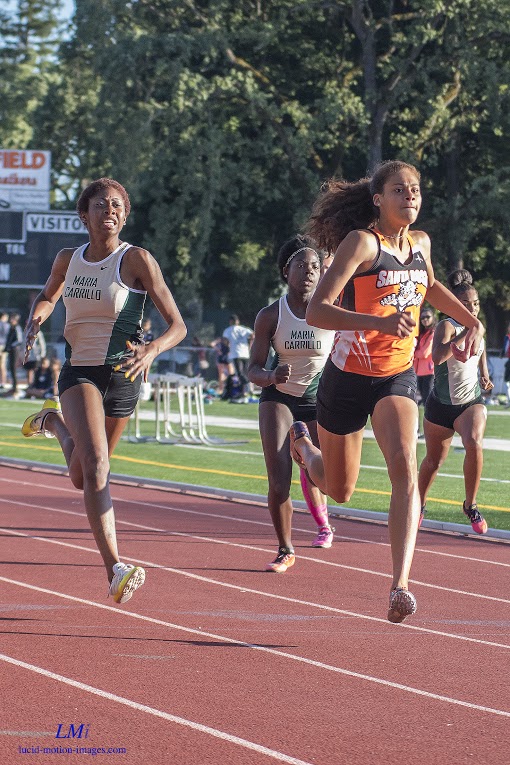 Athlete prepares for pole vault on a track with others watching.