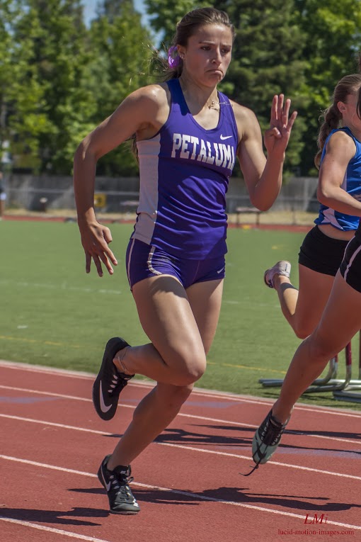 Athlete prepares for pole vault on a track with others watching.