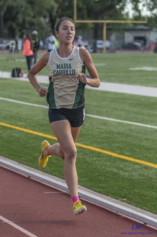 Athlete prepares for pole vault on a track with others watching.