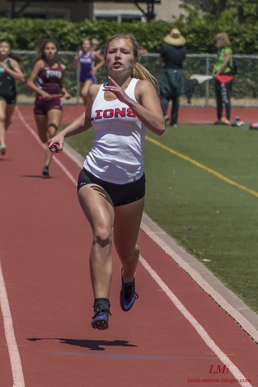 Athlete prepares for pole vault on a track with others watching.