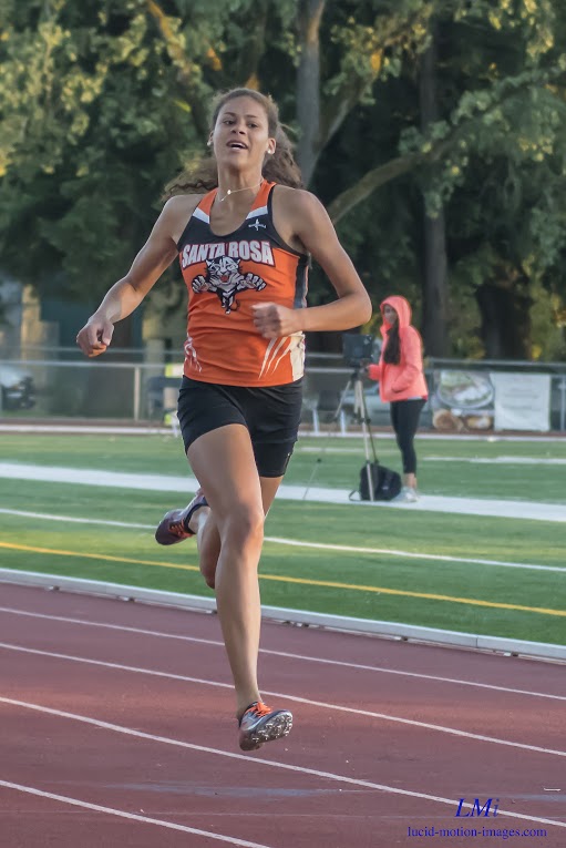 Athlete prepares for pole vault on a track with others watching.