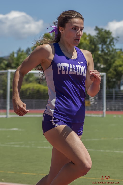 Athlete prepares for pole vault on a track with others watching.