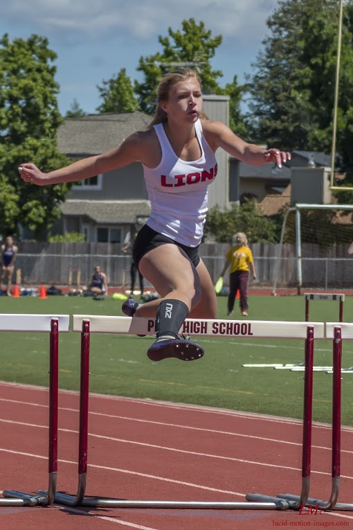 Athlete prepares for pole vault on a track with others watching.