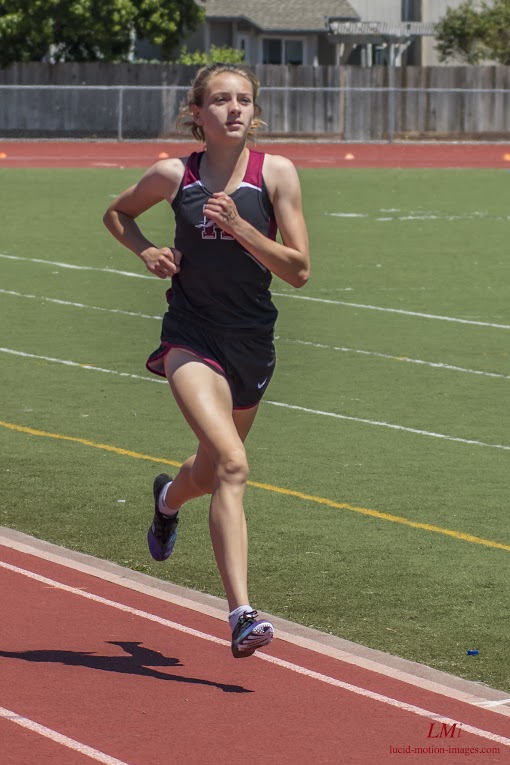 Athlete prepares for pole vault on a track with others watching.