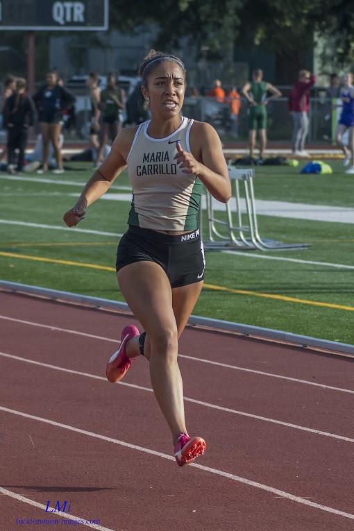 Athlete prepares for pole vault on a track with others watching.