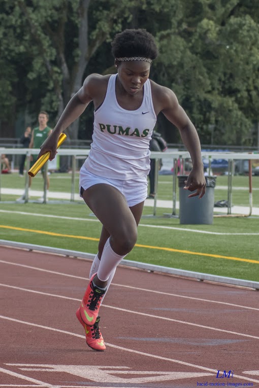 Athlete prepares for pole vault on a track with others watching.