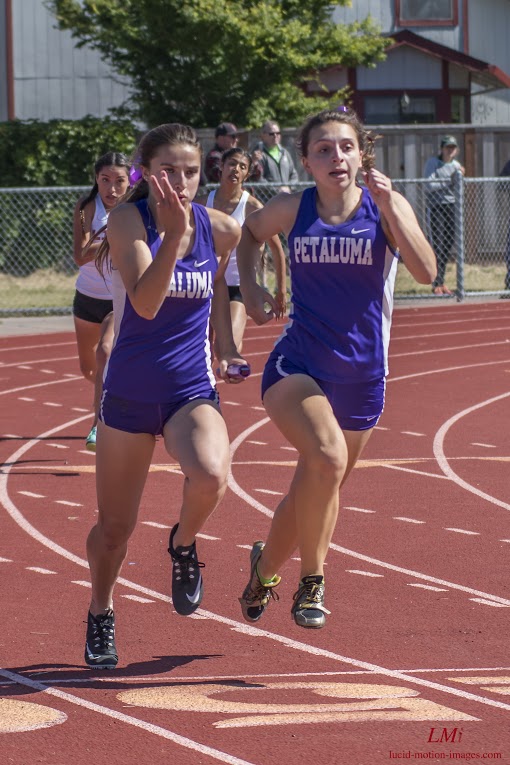 Athlete prepares for pole vault on a track with others watching.