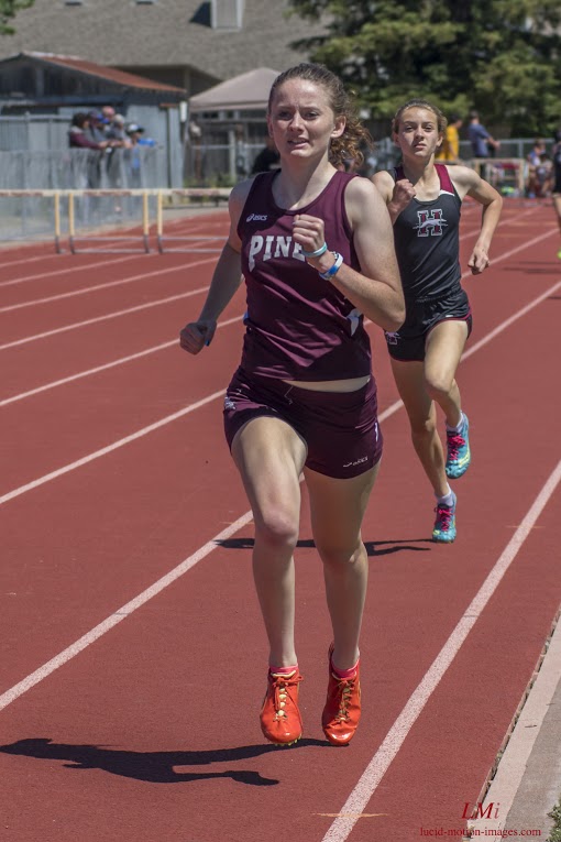 Athlete prepares for pole vault on a track with others watching.