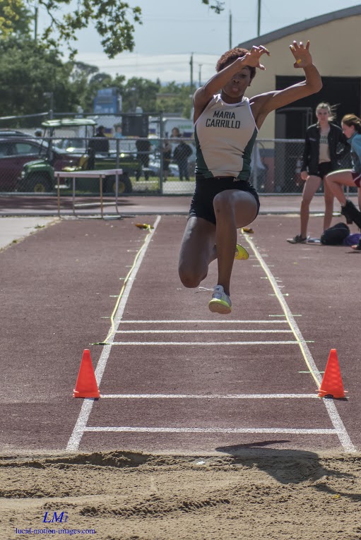 Athlete prepares for pole vault on a track with others watching.