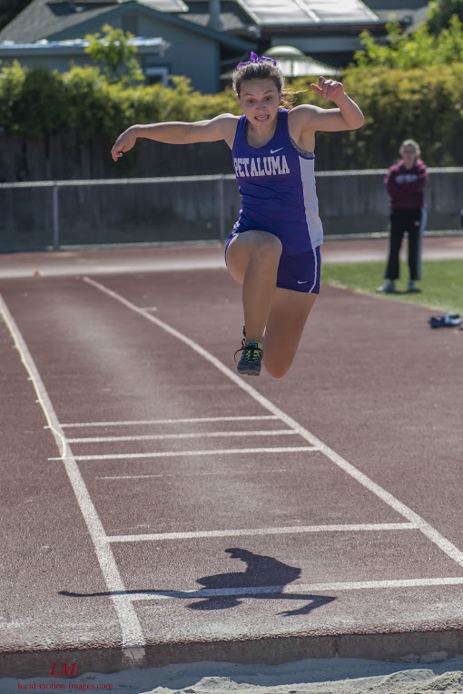 Athlete prepares for pole vault on a track with others watching.