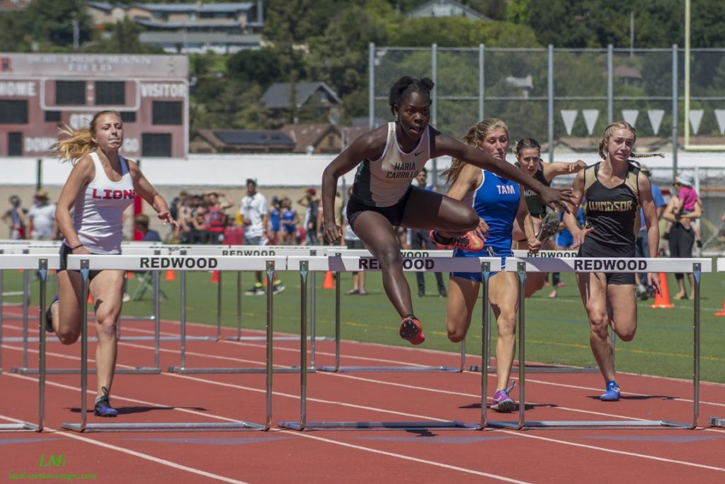 Athlete prepares for pole vault on a track with others watching.
