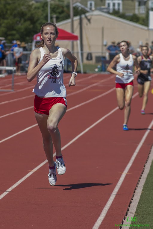 Athlete prepares for pole vault on a track with others watching.