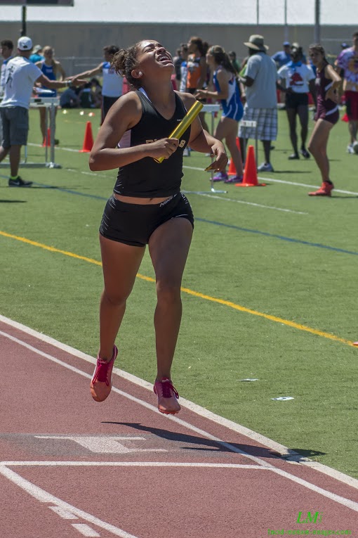 Athlete prepares for pole vault on a track with others watching.