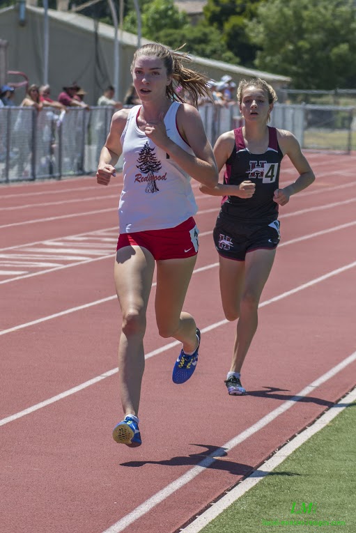 Athlete prepares for pole vault on a track with others watching.