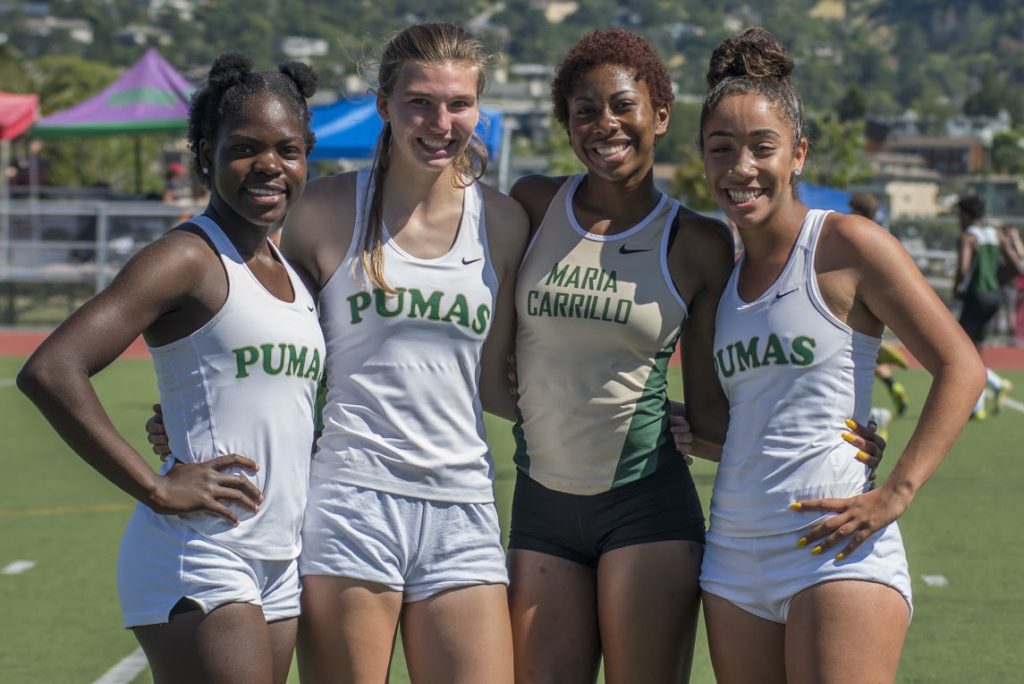 Athlete prepares for pole vault on a track with others watching.
