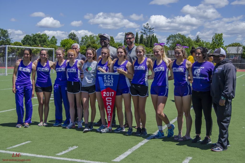 Athlete prepares for pole vault on a track with others watching.
