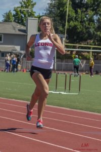 Athlete prepares for pole vault on a track with others watching.