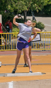 Young female athlete jumping during a track and field event.