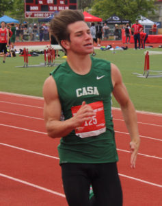 Athlete running on a track in a green Casa jersey.