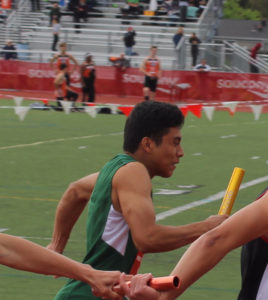 Athlete passing the baton in a relay race on a track field.